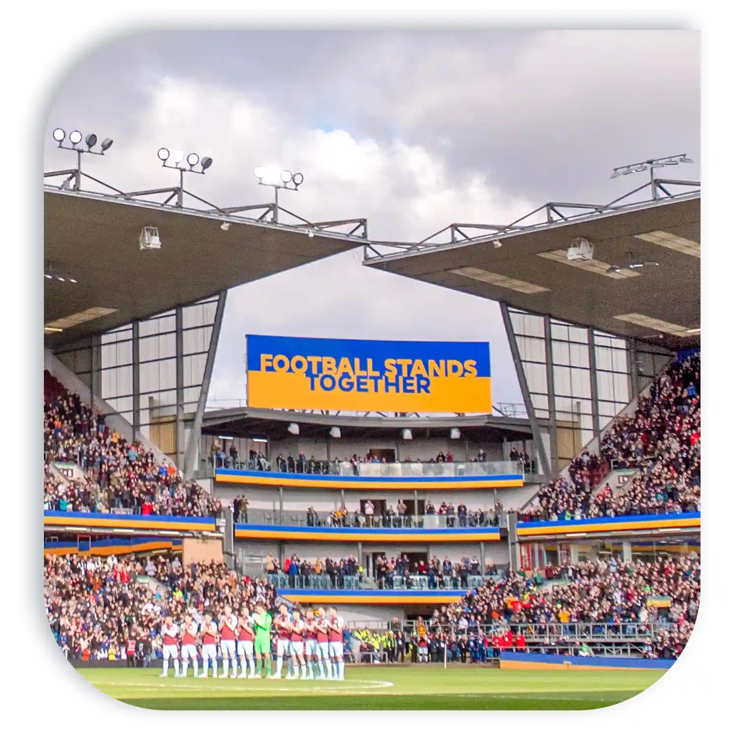 Football stadium with a large banner reading 'Football Stands Together' and spectators in the stands.