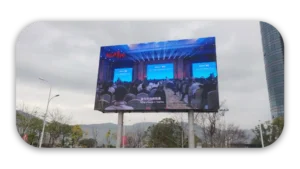 Outdoor LED display screen showing a conference presentation with an audience seated in front.