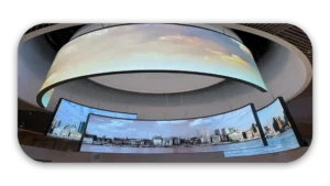 Multiple curved digital display screens showing cityscape and sky images in a modern setting.