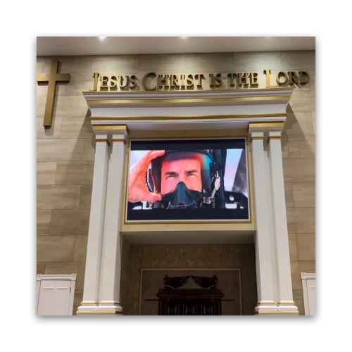 A large screen showing a pilot in a helmet, with a religious sign above it stating 'Jesus Christ is the Lord'.