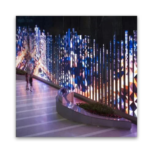 Colorful illuminated geometric wall installation with vertical panels in a modern setting.