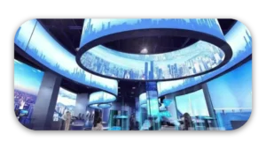Interior view of a modern exhibition space featuring large digital displays and curved screens.