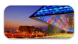 Architectural structure featuring a triangular design with colorful LED lighting at dusk.