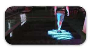 Individual walking on an interactive LED floor that lights up in response to movement.