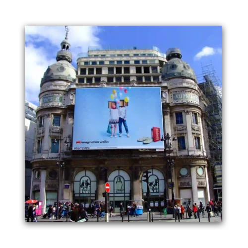 A large billboard on a historic building featuring a colorful advertisement with two people holding balloons.